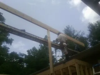 Carpenter setting a ridge beam over a new addition frame — Ice Dam Removal by Roofing Brothers in Defuniak Springs