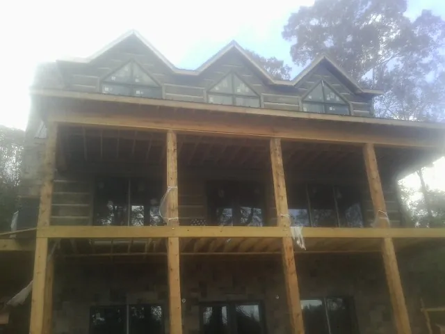 Dormers and porch framing on a large log home under construction — Roof Coating work by our crew in Defuniak Springs