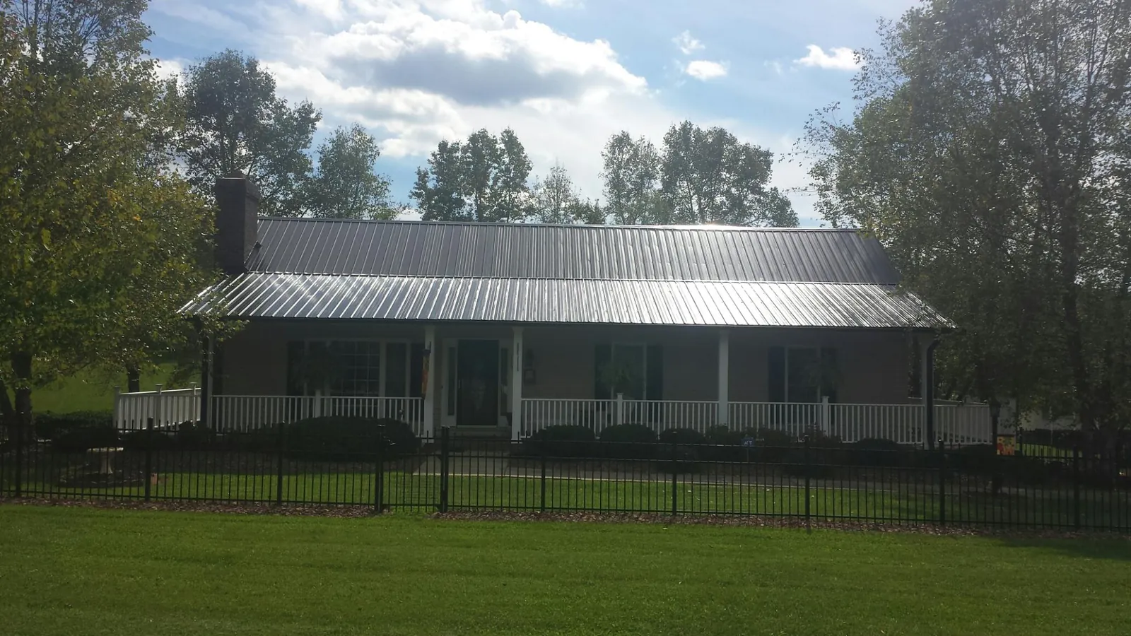 Gray metal roof on a brick ranch with a full width front porch — Gutter Guard Installation work by our crew in Defuniak Springs