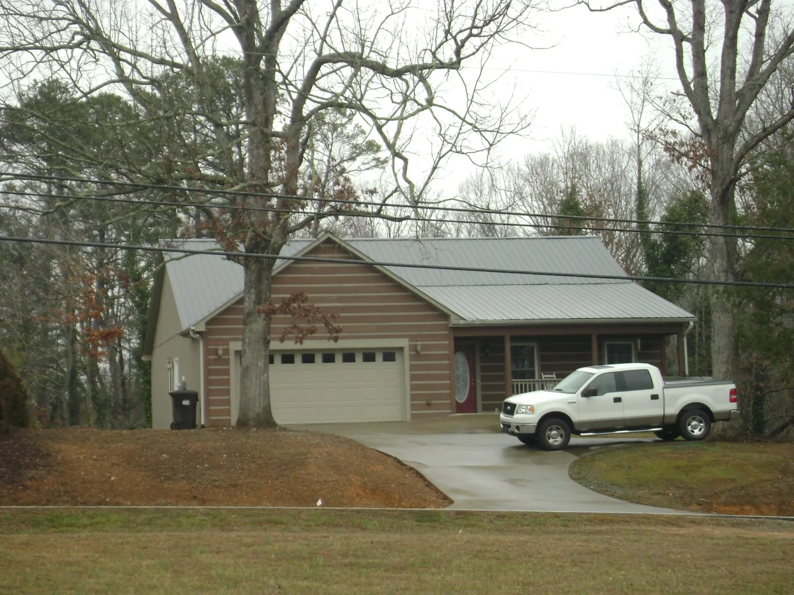 Gray metal roof on a log sided house with an attached two car garage in Defuniak Springs