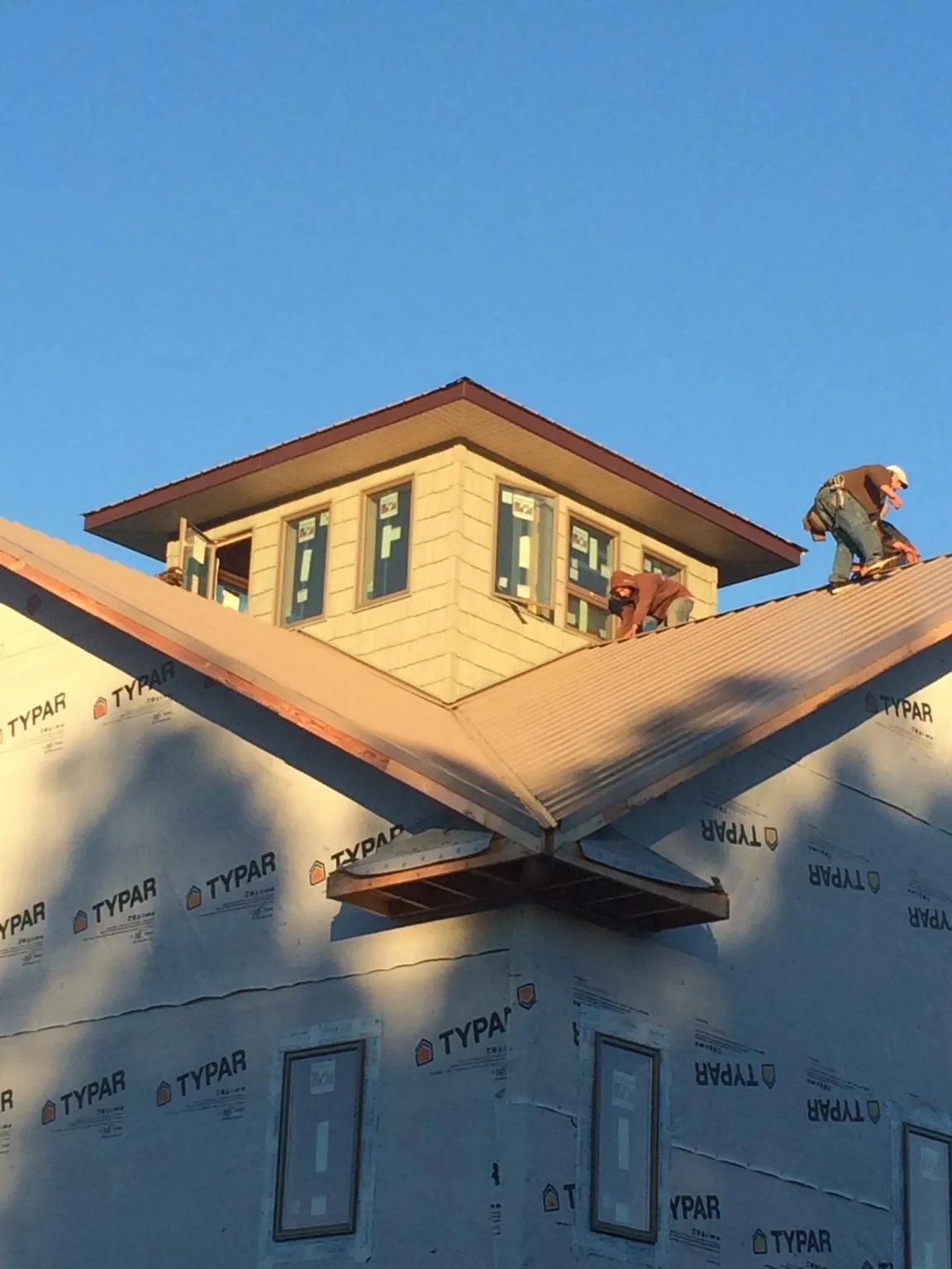 Roofers working around a rooftop cupola on a new metal roof at sunset — Roof Waterproofing in Defuniak Springs by Roofing Brothers